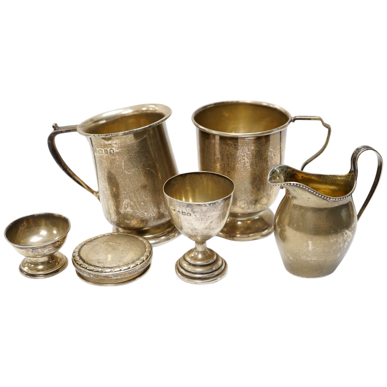 Six items of small silver:- two christening mugs, a cream jug, a salt, an egg cup and a box lid. Condition - poor to fair